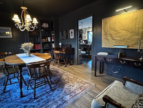 A dining area with a chandelier, wooden table, chairs, and a rug.