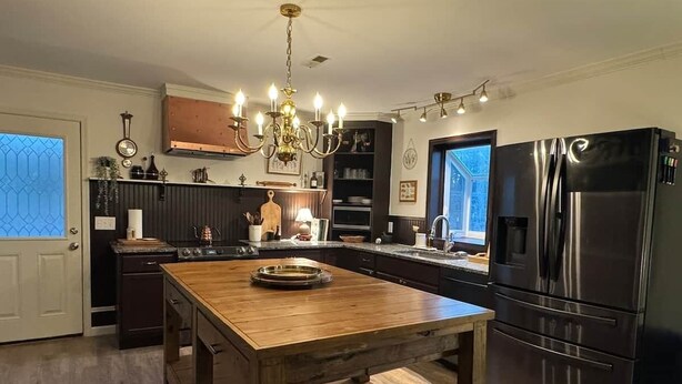 A kitchen with a wooden island, stainless steel appliances, and a chandelier.