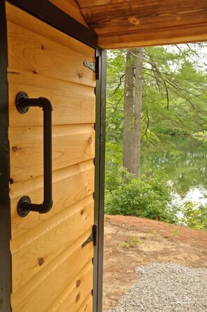 A wooden door with a metal handle and a view of a natural landscape with trees and a body of water.