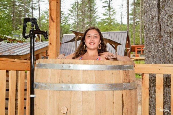 A wooden barrel with metal bands, a metal clamp, and a wooden fence.