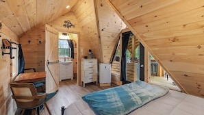 Acogedor dormitorio en el ático con cama, escritorio y pequeña kitchenette.