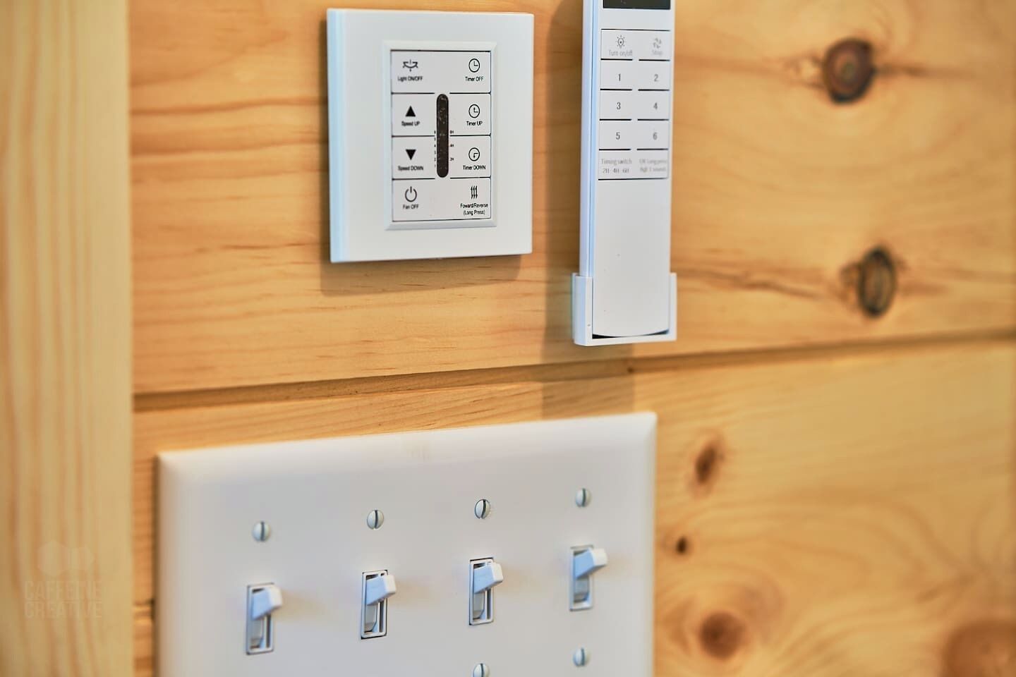 Un panneau de commande fixé au mur, doté d’un minuteur et d’une télécommande, ainsi qu’un ensemble d’interrupteurs situés en dessous.