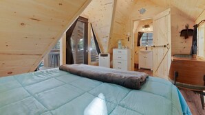 Un dormitorio acogedor en el ático, con cama, cómoda, tocador y una mesita.