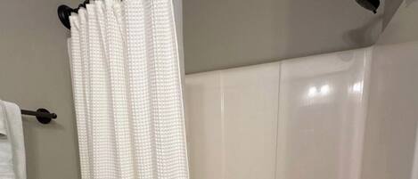 Une salle de bain avec une baignoire, un rideau de douche et un porte-serviettes.
