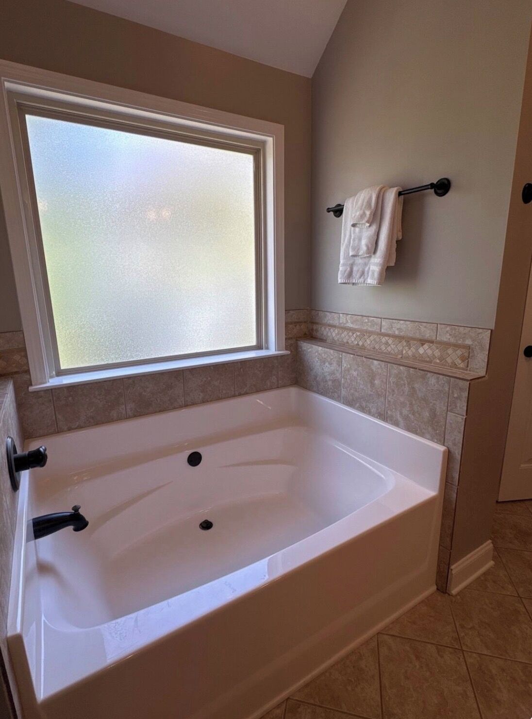 Une salle de bain avec une grande baignoire, une fenêtre et un porte-serviettes.