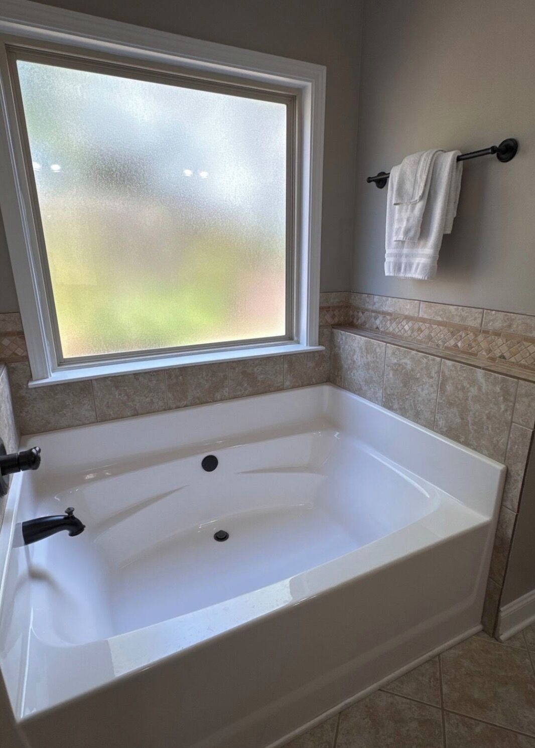 Ein Badezimmer mit freistehender Badewanne, einem Fenster und einem Handtuchhalter.