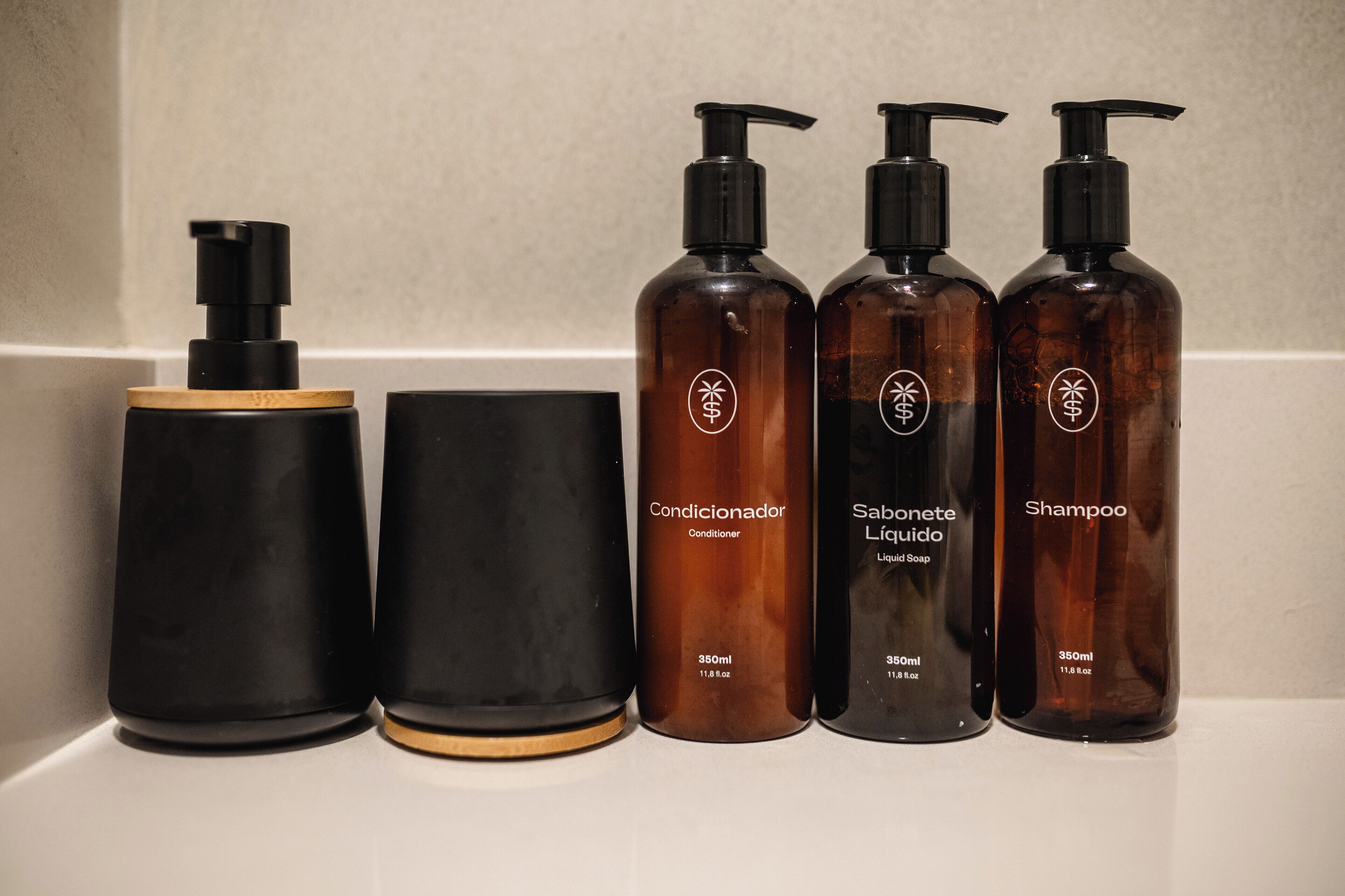 Cuatro botellas de productos para el cabello sobre una encimera de baño.