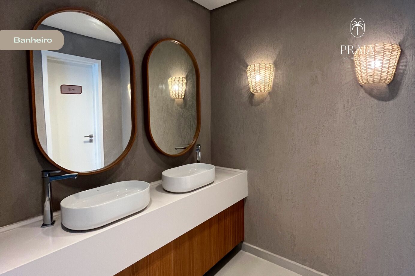 Ein Badezimmer mit zwei ovalen Waschbecken, einem Spiegel mit Holzrahmen und einer Wandleuchte.