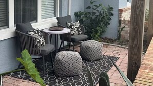 Un espacio de patio cubierto con una pérgola de madera, una mesa con sillas y una planta en maceta.