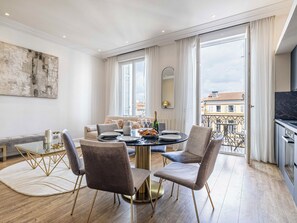A modern living room with a dining area, large windows, and a view of the city. - 3-bedroom apartment Rue d'Antibes near the Palais (Cannes)