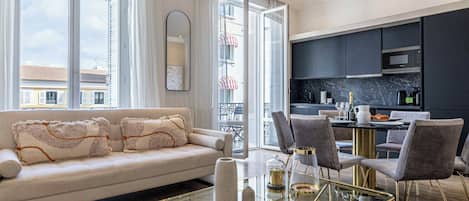 A modern living room with a glass coffee table, a sofa with decorative pillows, and a view of the city through large windows.