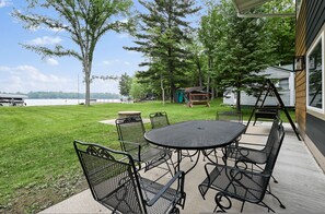 A patio with a round table and chairs, a swing set, and a view of a lake. - 5 BR Family Hangout I Lake Views I Firepit (Suring)