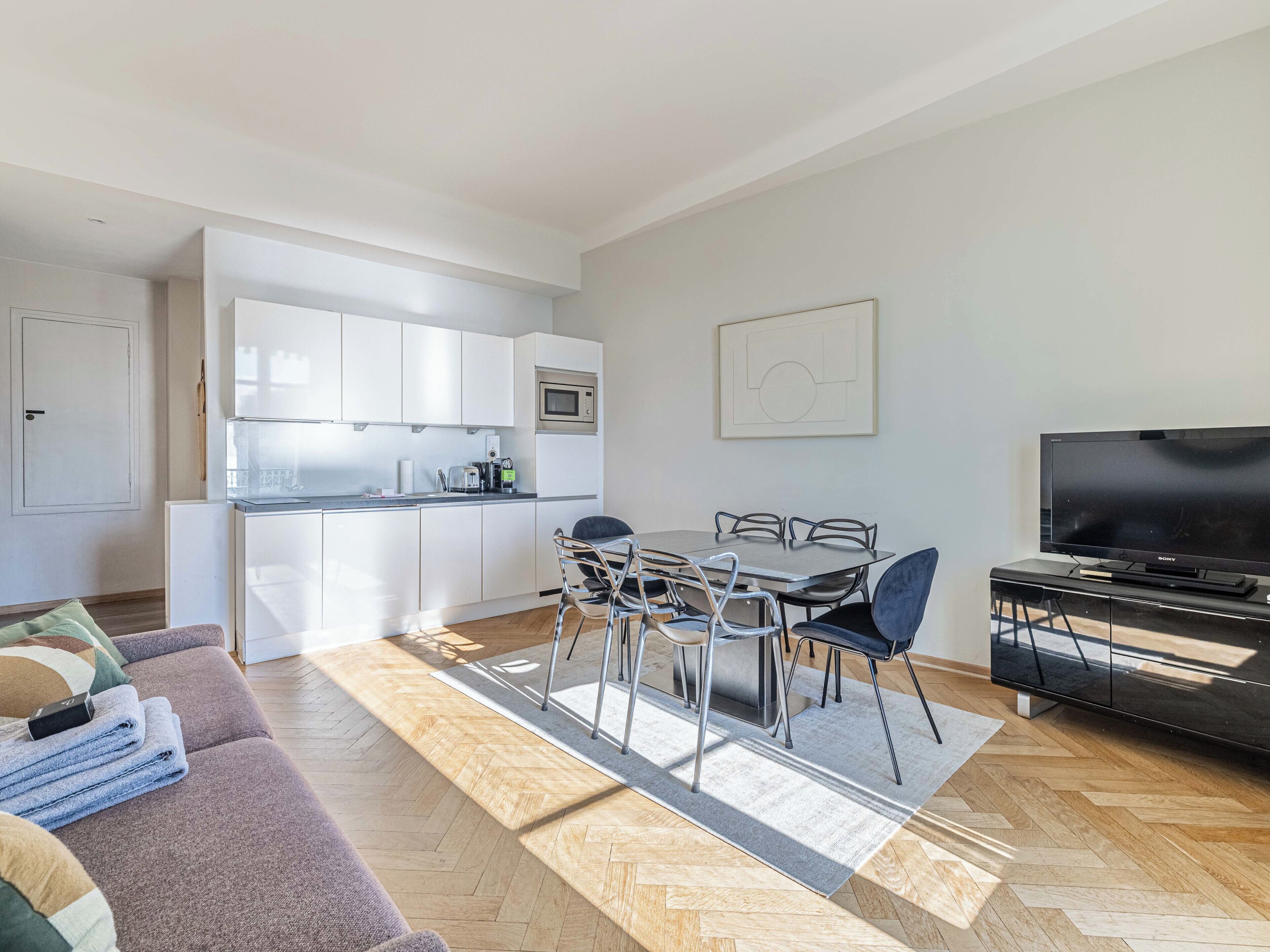 A modern apartment with a kitchen, dining area, and living room.