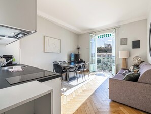 Une cuisine moderne avec un coin repas, un canapé et une vue sur la ville depuis un balcon.
