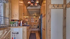 A narrow wooden hallway with a kitchen area on one side, featuring wooden cabinets, a refrigerator, and a dining table. - 4 BR A-Frame Cabin- 15 mins to Winter Park (Tabernash)