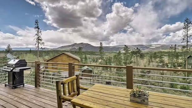 A wooden deck with a grill and a table, overlooking a mountainous landscape. - 4 BR A-Frame Cabin- 15 mins to Winter Park (Tabernash)