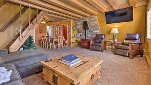 A cozy living room with a wooden coffee table, leather chairs, a staircase, and a stone wall. - 4 BR A-Frame Cabin- 15 mins to Winter Park (Tabernash)