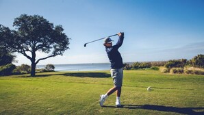 A person playing golf on a sunny day with a clear sky and a tree in the background. - Currituck Club Resort Usage-NOT A RENTAL OF LIVING SPACE: Please read descript (Corolla)