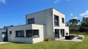 A modern two-story house with a flat roof, large windows, and a well-maintained lawn. - Modern house near the sea (Trébeurden)