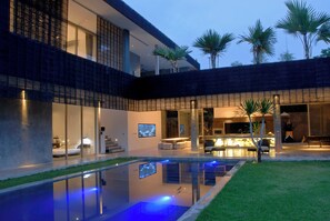 A modern house with a swimming pool, outdoor seating, and palm trees. - Modern 4BD Villa with Pool in Seminyak (Seminyak)