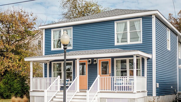 A two-story house with a porch, a front door, and a garage. - New! By Park-Family Friendly-Fenced Yard-Fire Pit! Walk to Central Park & Beach! (Cape Charles)