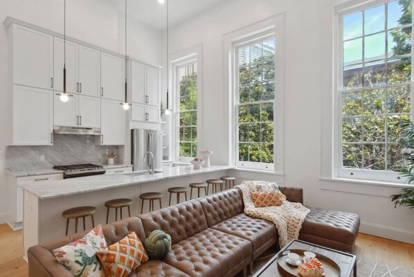 A modern kitchen with white cabinets, a central island, and pendant lighting.