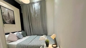 A bedroom with a bed, a desk with a laptop, a small plant, and a wall-mounted picture. - The Hive Partition Room in Tecom (Dubai)