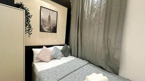A bedroom with a bed, pillows, a blanket, a framed picture on the wall, and a curtain. - The Hive Partition Room in Tecom (Dubai)