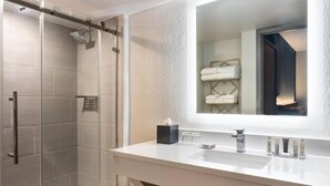 A modern bathroom with a glass-enclosed shower, a white vanity with dual sinks, and a large mirror.