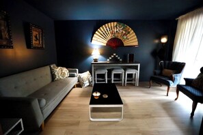 A modern living room with a sofa, a coffee table, a fan, and a chair.