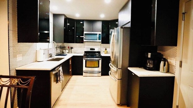 Una cocina compacta con armarios oscuros, un microondas, una estufa y un refrigerador.