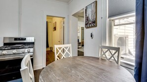 Een keuken met een fornuis, oven en eettafel met stoelen.