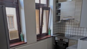 A compact kitchen with a dining area, featuring a built-in oven, a microwave, and a small refrigerator.