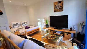 Uma sala de estar moderna com uma cama, um sofá, uma televisão e uma mesa de centro.