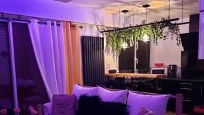 Uma sala de estar moderna com um sofá branco, uma mesa de centro de vidro e uma planta pendurada.