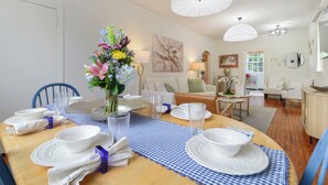 A dining area with a wooden table set for four, a vase of flowers, and a blue and white checkered table runner. - Historic Uptown New Orleans 2BR – 1 Block to St. Charles Streetcar (New Orleans)