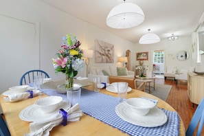A dining area with a wooden table set for four, a vase of flowers, and a blue and white checkered table runner. - Historic Uptown New Orleans 2BR – 1 Block to St. Charles Streetcar (New Orleans)