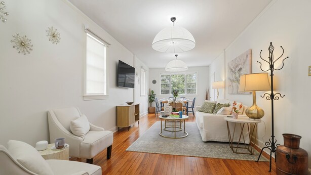 A living room with a sofa, armchair, coffee table, and decorative items. - Historic Uptown New Orleans 2BR – 1 Block to St. Charles Streetcar (New Orleans)
