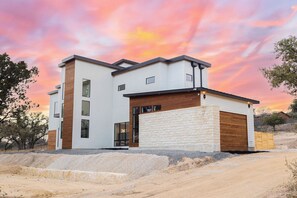 A modern two-story house with a garage, large windows, and a stone facade. - Private High-end Resort•Pool•Hottub•Rooftop Movie Theater•Walk to River•Firepit (Concan)