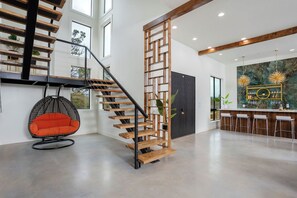 A modern interior with a wooden staircase, a hanging chair, and a bar area. - Private High-end Resort•Pool•Hottub•Rooftop Movie Theater•Walk to River•Firepit (Concan)