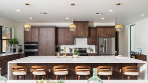 Een moderne keuken met een centraal eiland, barkrukken en hanglampen.