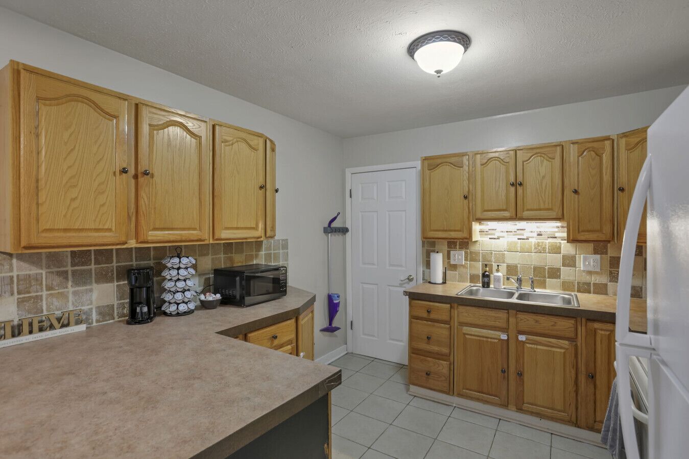A kitchen with wooden cabinets, a microwave, a coffee maker, and a sink.