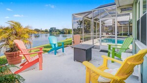 Un espacio al aire libre cubierto con una piscina, varias sillas Adirondack y vistas a un lago.