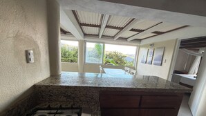 Una cocina con estufa a gas, encimeras de granito y vistas al exterior.