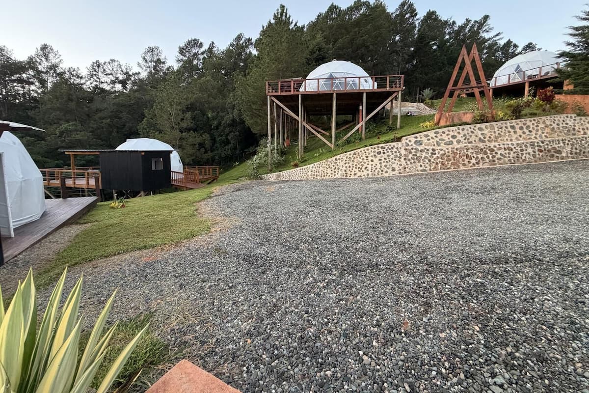 Un campamento con tiendas de forma abovedada, una terraza de madera y un muro de piedra.
