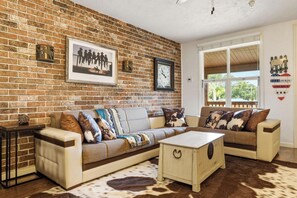 A living room with a brick wall, a sofa set, a coffee table, and a cowhide rug. - River Ranch  Oasis / Wild West Escape (River Ranch)