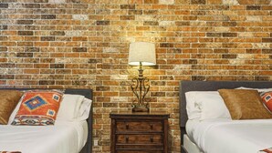 A room with two beds, a nightstand, and a brick wall. - River Ranch  Oasis /  Wild West Escape (River Ranch)