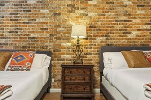 A room with two beds, a nightstand, and a brick wall. - River Ranch  Oasis /  Wild West Escape (River Ranch)