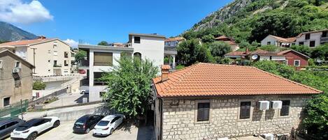 Zona residencial con edificios de piedra, un estacionamiento y montañas al fondo.