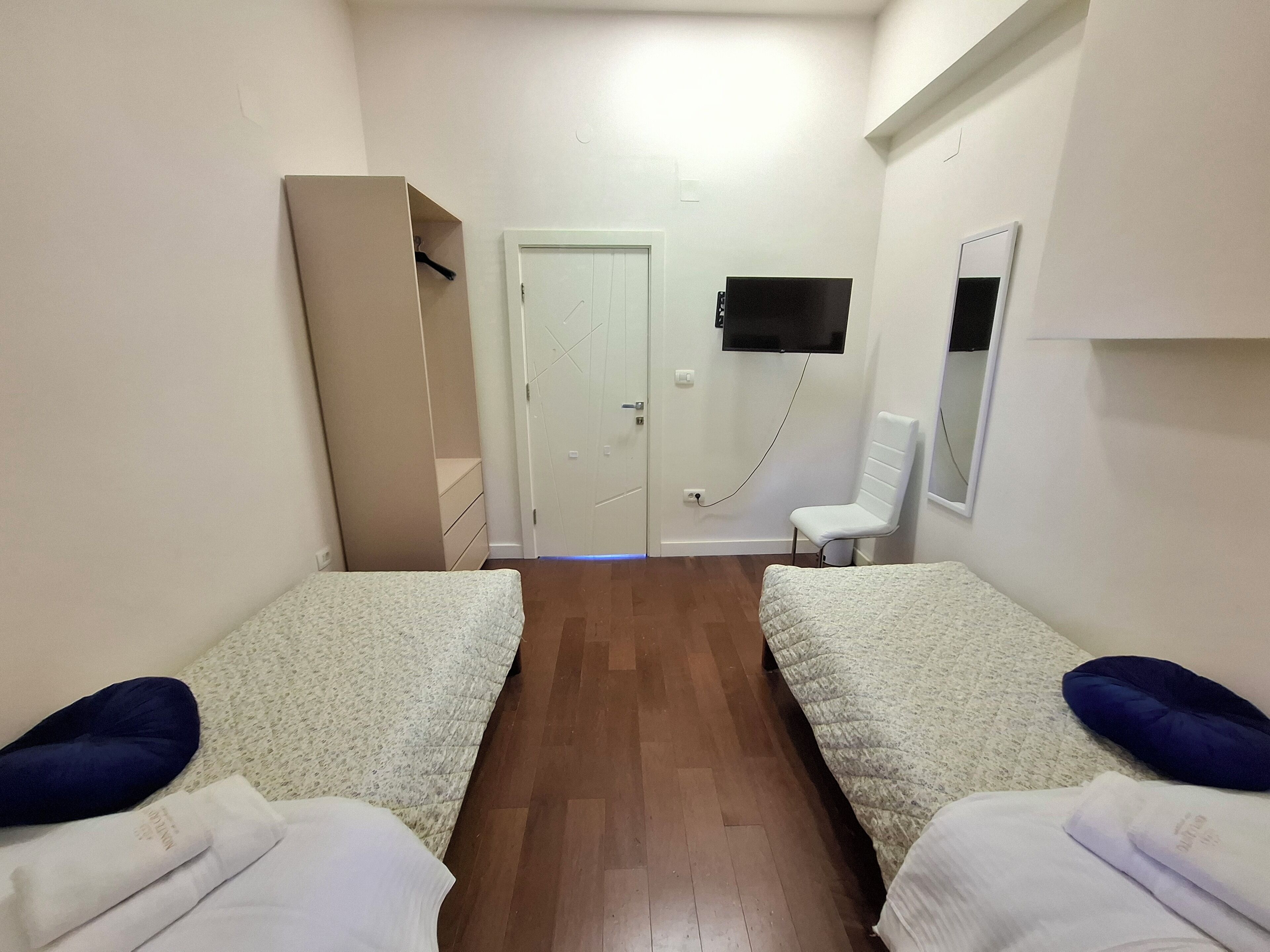 Una habitación con dos camas, un armario, un televisor y un espejo.